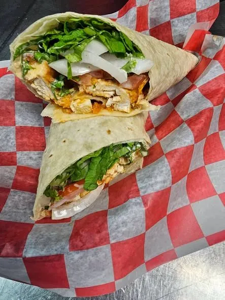 Buffalo chicken wrap cut in half, loaded with lettuce, tomato, and onion