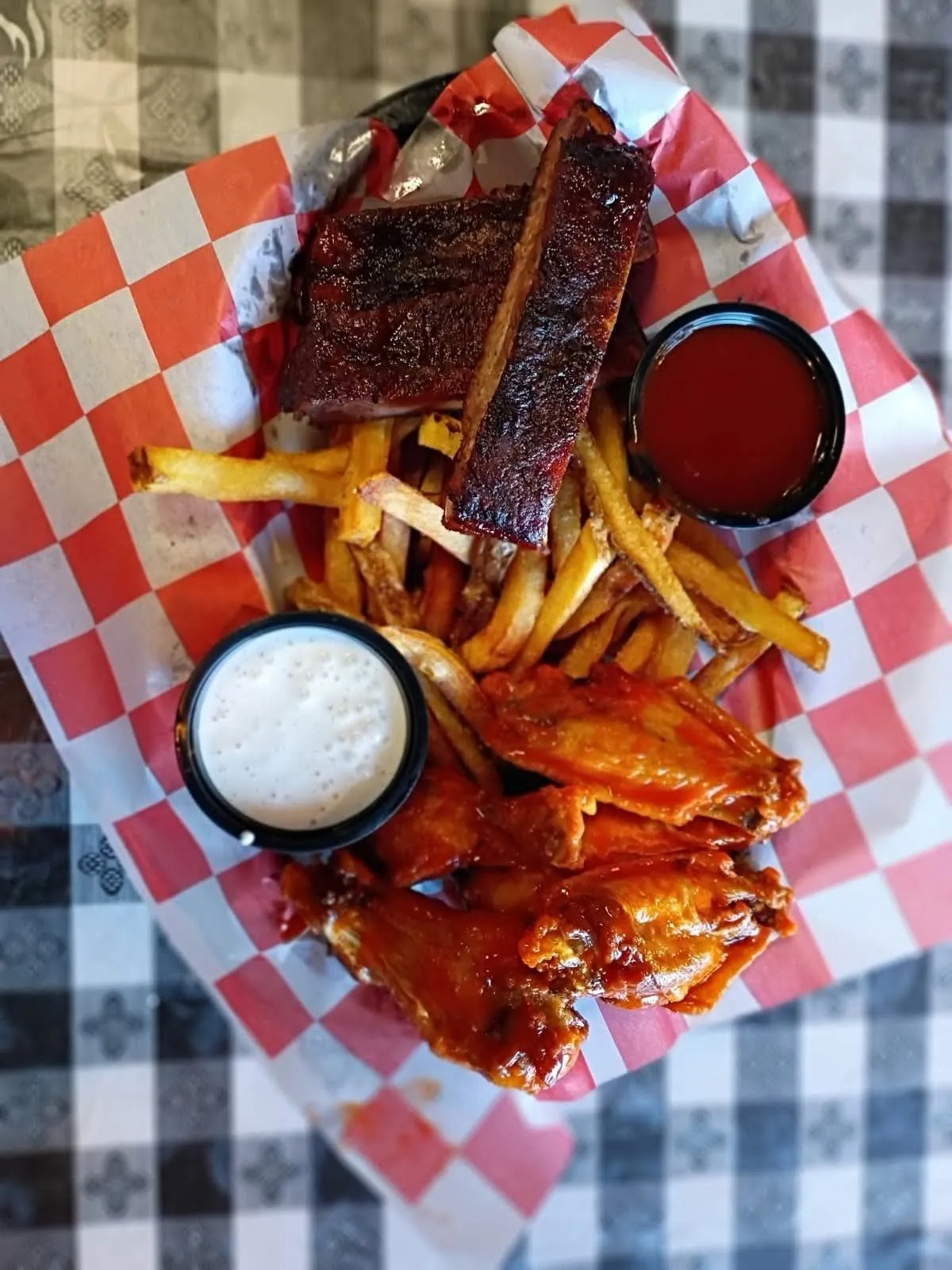 Rib and wing basket with fresh-cut fries and ranch in a red-checkered basket