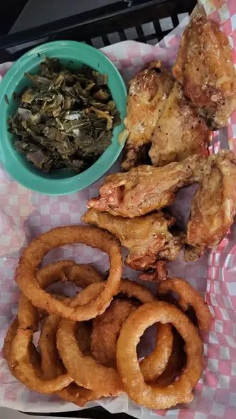 Basket of glazed wings with onion rings and collard greens