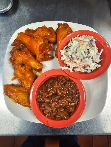 Buffalo wings plated with coleslaw and baked beans